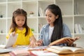 An adorable little Asian preschool girl is studying English alphabet flashcards with a teacher