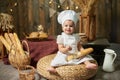 Adorable little baby baker with a French baguette in a rustic interior