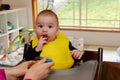 Adorable little baby boy in feeding chair being spoon fed by his mother Royalty Free Stock Photo