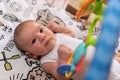 Adorable little baby boy lying on his back surrounded by colourful toys Royalty Free Stock Photo