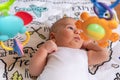 Adorable little baby boy lying on his back surrounded by colourful toys Royalty Free Stock Photo