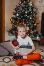 adorable little baby boy sitting in front of a christmas tree. Christmas Child Open Present Gift, Happy Baby Boy looking Royalty Free Stock Photo