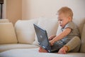 Adorable little baby boy sitting on a sofa and playing with toy computer. Cute little childs feet, boy playing Royalty Free Stock Photo
