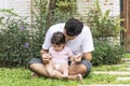 Little baby daughter sitting on her father scoop while rest in the garden at home. Handsome single dad holding and Royalty Free Stock Photo