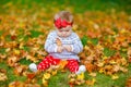 Adorable little baby girl in autumn park on sunny warm october day with oak and maple leaf. Fall foliage. Family outdoor Royalty Free Stock Photo