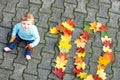 Adorable little baby girl in autumn park on sunny warm october day with oak and maple leaf. Fall foliage. Family outdoor Royalty Free Stock Photo