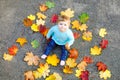 Adorable little baby girl in autumn park on sunny warm october day with oak and maple leaf. Fall foliage. Family outdoor Royalty Free Stock Photo