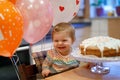 Adorable little baby girl celebrating first birthday. Baby eating marshmellows decoration on homemade cake, indoor. Royalty Free Stock Photo