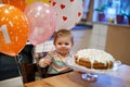 Adorable little baby girl celebrating first birthday. Baby eating marshmellows decoration on homemade cake, indoor. Royalty Free Stock Photo