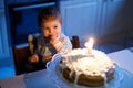 Adorable little baby girl celebrating first birthday. Child blowing one candle on homemade baked cake, indoor. Royalty Free Stock Photo