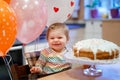 Adorable little baby girl celebrating first birthday. Baby eating marshmellows decoration on homemade cake, indoor Royalty Free Stock Photo