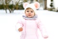Adorable little baby girl making first steps outdoors in winter. Cute toddler learning walking. Child having fun on cold Royalty Free Stock Photo