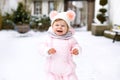 Adorable little baby girl making first steps outdoors in winter. Cute toddler learning walking. Royalty Free Stock Photo