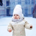 Adorable little baby girl making first steps outdoors in winter. Cute toddler learning walking. Child having fun on cold Royalty Free Stock Photo