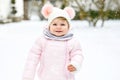 Adorable little baby girl making first steps outdoors in winter. Cute toddler learning walking. Royalty Free Stock Photo