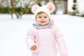 Adorable little baby girl making first steps outdoors in winter. Cute toddler learning walking. Royalty Free Stock Photo