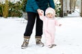 Adorable little baby girl making first steps outdoors in winter with mother. Cute toddler learning walking. Royalty Free Stock Photo