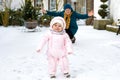 Adorable little baby girl making first steps outdoors in winter with mother. Cute toddler learning walking. Royalty Free Stock Photo