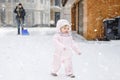 Adorable little baby girl making first steps outdoors in winter through snow. Cute toddler child learning walking. On Royalty Free Stock Photo