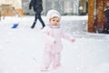 Adorable little baby girl making first steps outdoors in winter through snow. Cute toddler child learning walking. On Royalty Free Stock Photo