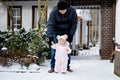 Adorable little baby girl making first steps outdoors in winter through snow. Cute toddler learning walking. Father Royalty Free Stock Photo