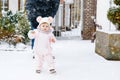 Adorable little baby girl making first steps outdoors in winter through snow. Cute toddler learning walking. Father Royalty Free Stock Photo