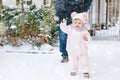 Adorable little baby girl making first steps outdoors in winter through snow. Cute toddler learning walking. Father Royalty Free Stock Photo