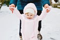 Adorable little baby girl making first steps outdoors in winter through snow. Cute toddler learning walking. Mother Royalty Free Stock Photo