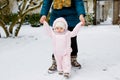 Adorable little baby girl making first steps outdoors in winter through snow. Cute toddler learning walking. Mother Royalty Free Stock Photo