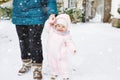 Adorable little baby girl making first steps outdoors in winter through snow. Cute toddler learning walking. Mother Royalty Free Stock Photo