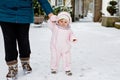 Adorable little baby girl making first steps outdoors in winter through snow. Cute toddler learning walking. Mother Royalty Free Stock Photo