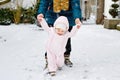 Adorable little baby girl making first steps outdoors in winter through snow. Cute toddler learning walking. Mother Royalty Free Stock Photo