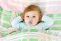 Adorable little baby girl after sleeping in bed. Calm peaceful child with a pacifier or dummy