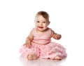 Adorable little baby girl in stylish pink princess dress and barefoot is sitting on floor happy smiling Royalty Free Stock Photo