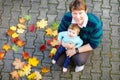 Adorable little baby girl and young father in autumn park on sunny warm october day with oak and maple leaf. Fall Royalty Free Stock Photo