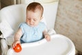 little baby sitting in her chair and playing with vegetables . small girl eat tomato. healthy food for children Royalty Free Stock Photo