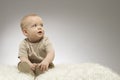 Adorable little baby sitting on the white blanket, studio shot, isolated on grey background, lovely baby portrait Royalty Free Stock Photo