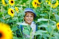 Adorable little blond kid boy with glasses and hat on summer sunflower field outdoors. Cute preschool child having fun Royalty Free Stock Photo