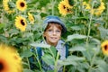 Adorable little blond kid boy with glasses and hat on summer sunflower field outdoors. Cute preschool child having fun Royalty Free Stock Photo