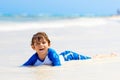 Adorable little blond kid boy having fun on tropical beach of Jamaica. Excited child playing and surfing in sun Royalty Free Stock Photo