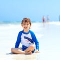 Adorable little blond kid boy having fun on tropical beach of Jamaica. Excited child playing and surfing in sun Royalty Free Stock Photo