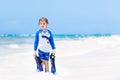 Adorable little blond kid boy having fun on tropical beach of Maldives. Excited child playing and surfing in sun Royalty Free Stock Photo