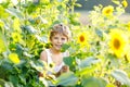 Adorable little blond kid boy on summer sunflower field outdoors. Cute preschool child having fun on warm summer evening Royalty Free Stock Photo