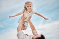 Adorable little blonde girl playing outside with her father against a clear blue sky. Cute female child smiling and Royalty Free Stock Photo