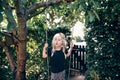 Adorable little blonde girl playing outside on a tree swing Royalty Free Stock Photo