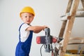 Child with electric drill standing on construction ladder. Royalty Free Stock Photo