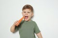 Adorable little boy eating carrot on white background. Royalty Free Stock Photo