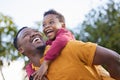 Lets go higher, dad. an adorable little boy enjoying a piggyback ride with his father in a garden. Royalty Free Stock Photo