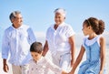 Adorable little boy and girl holding hands while walking along the beach with their grandparents during summer vacation Royalty Free Stock Photo
