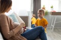 Adorable little boy looking at his mother pregnant tummy, woman sitting on sofa and talking with her toddler son Royalty Free Stock Photo